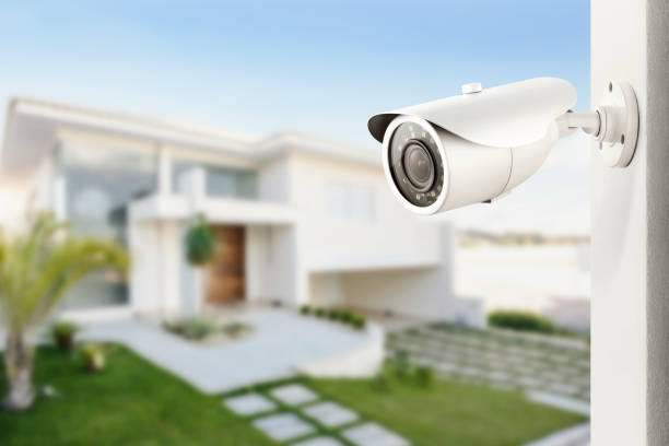 Services three quarter view of varifocal surveillance camera, with a house on background